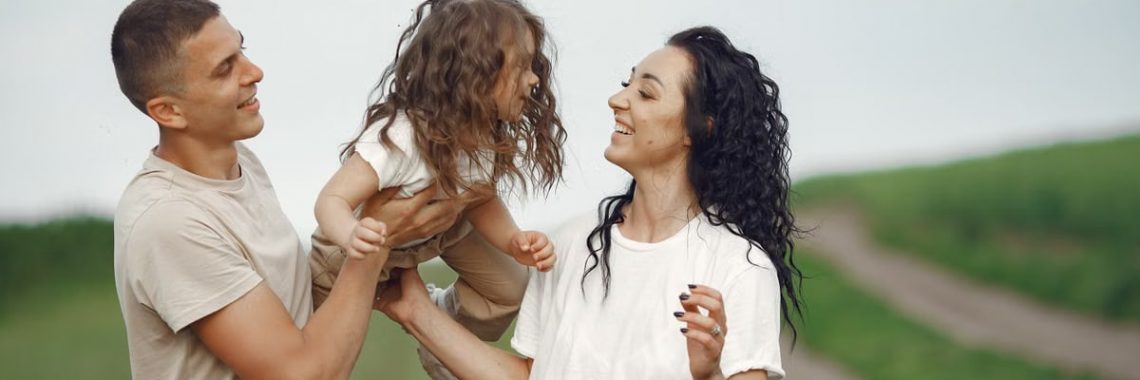 A joyful family moment outdoors with parents playing with their daughter.